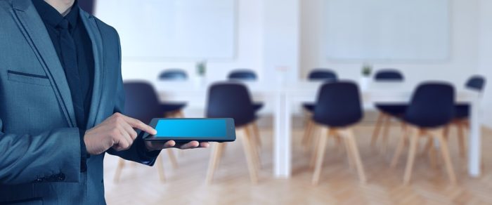 homem com smartphone na mão em um sala com cadeiras ao fundo